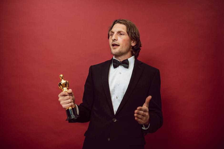 An accomplished man in a tuxedo holding a trophy, symbolizing triumph and recognition, against a red backdrop