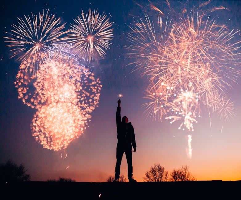 A person celebrates under vibrant fireworks in the evening sky in Kragujevac, Serbia
